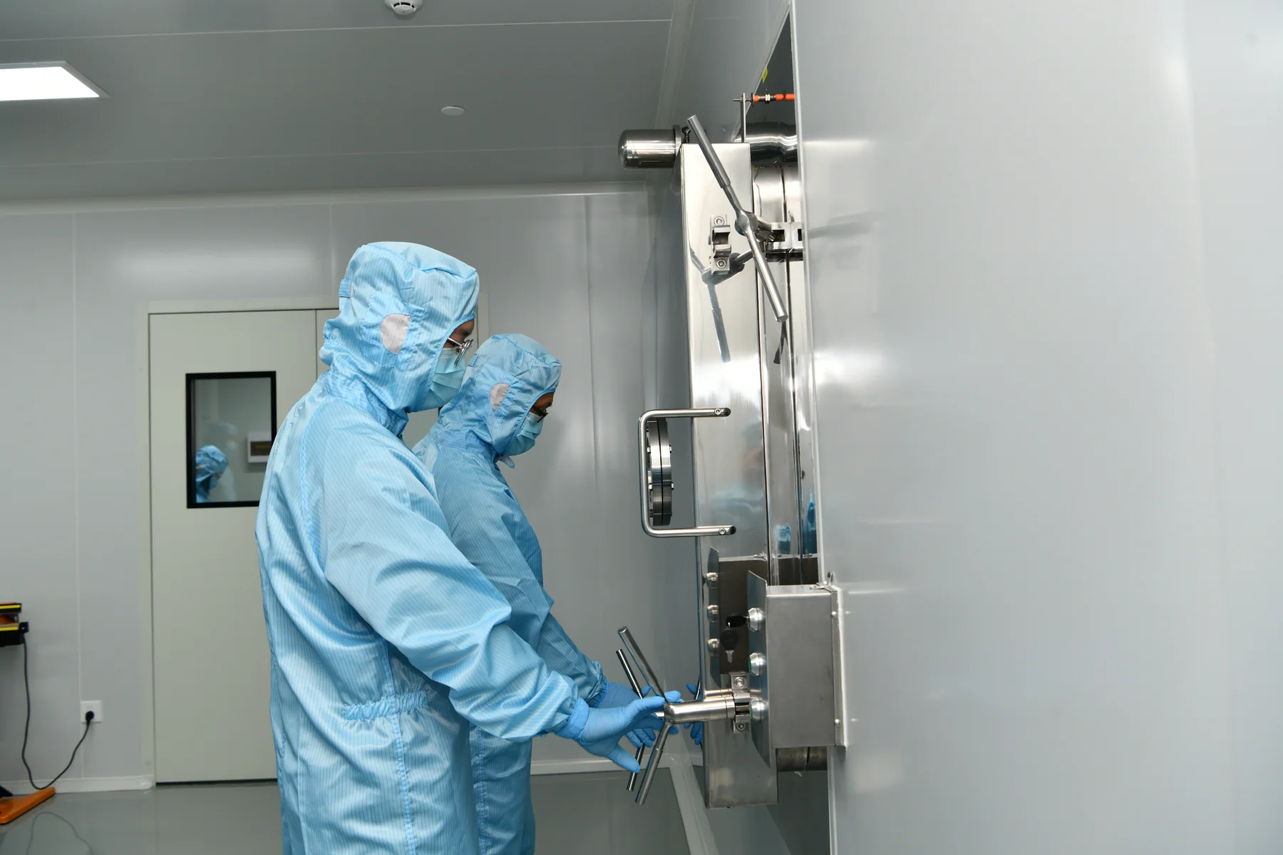 Operators in cleanroom garments at stainless processing equipment